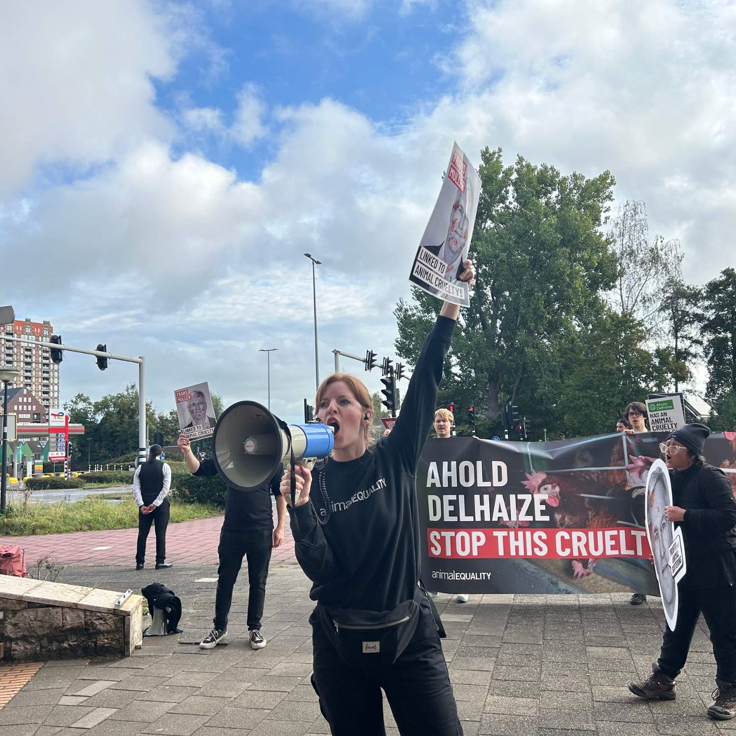 Ativista levanta cartaz e fala no megafone durante protesto em frente a sede da Ahold Delhaize