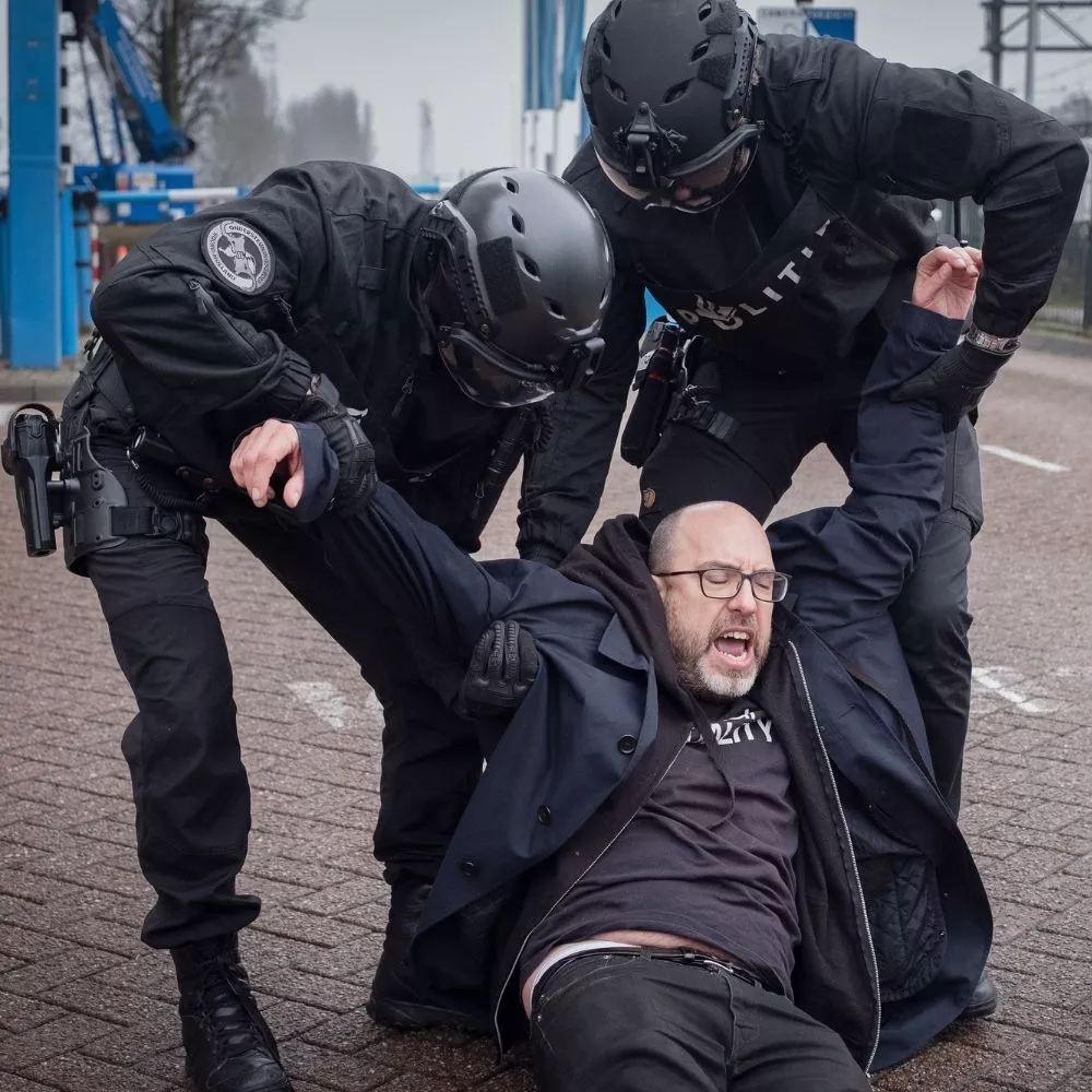Javi sendo levado por dois policiais em protesto contra a rede varejista Ahold Delhaize